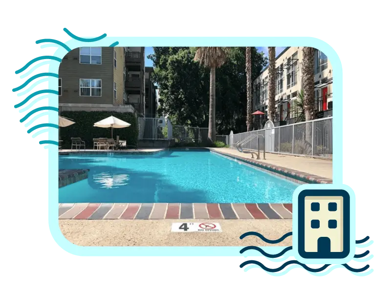 Apartment complex pool with nice shaded areas with umbrellas and chairs for seating and large palms growing around the perimeter.